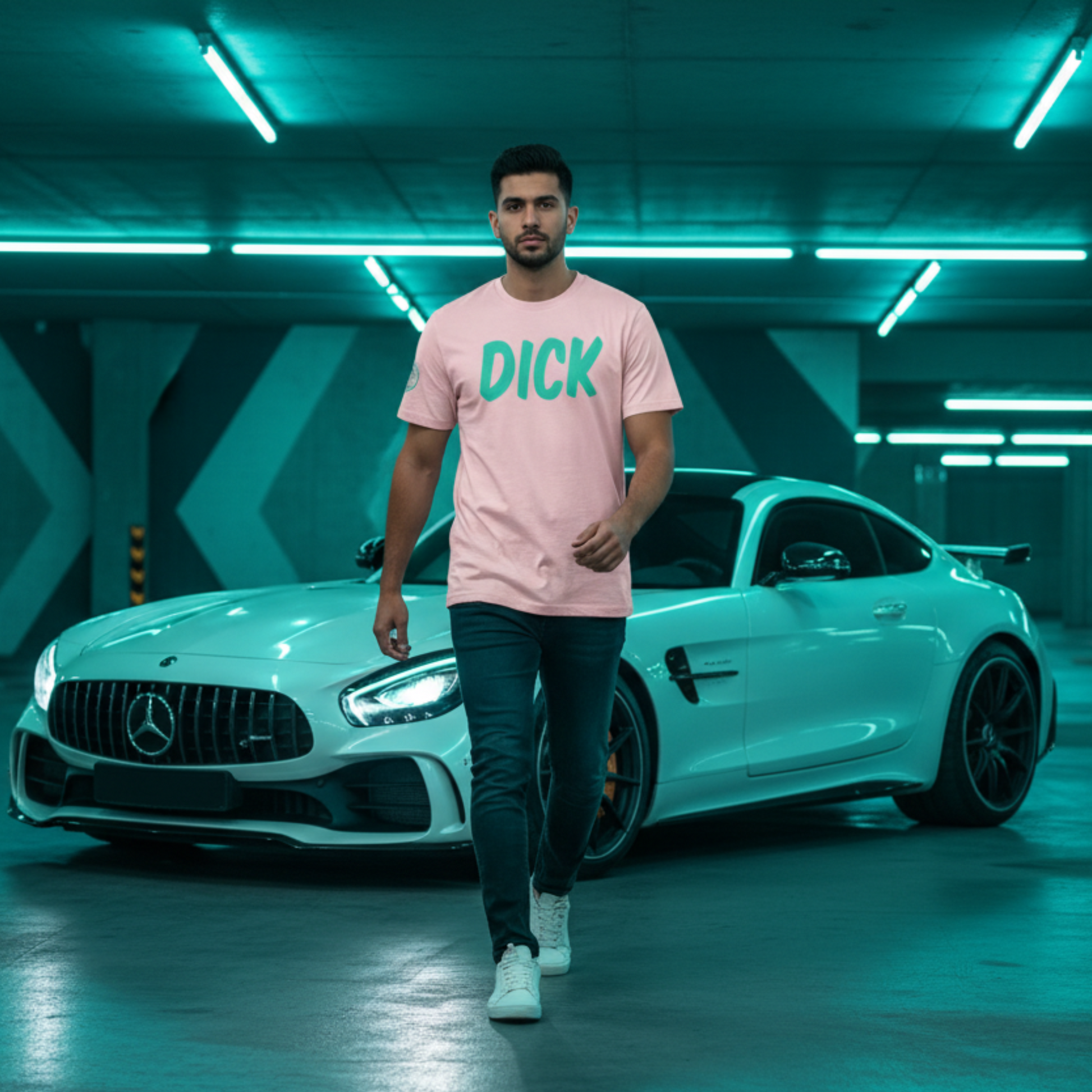 Man wearing a pink car t-shirt with 'DICK' printed on it in teal, standing in front of a white Mercedes-Benz car in a garage.