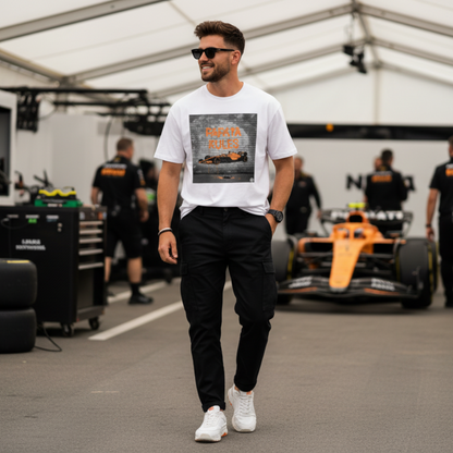 Male model wearing the white organic cotton Papaya Rules graffiti art t-shirt in a motorsport paddock setting, styled with modern casual fashion and motorsport props.