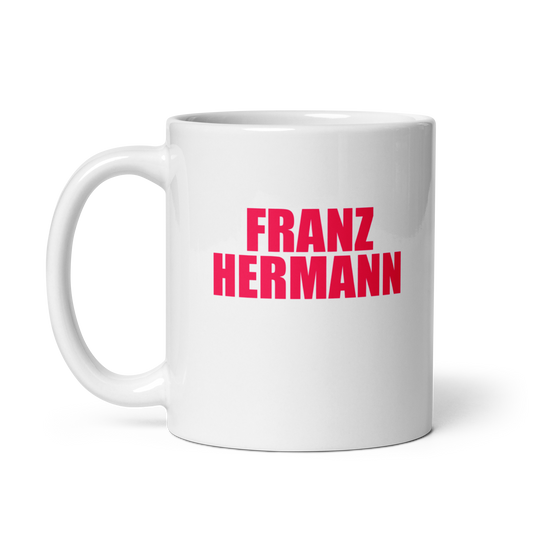 White mug with red bull pink text 'FRANZ HERMANN' on a white background. Handle on left.