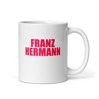 White mug with red bull pink text 'FRANZ HERMANN' on a white background. Handle on right.