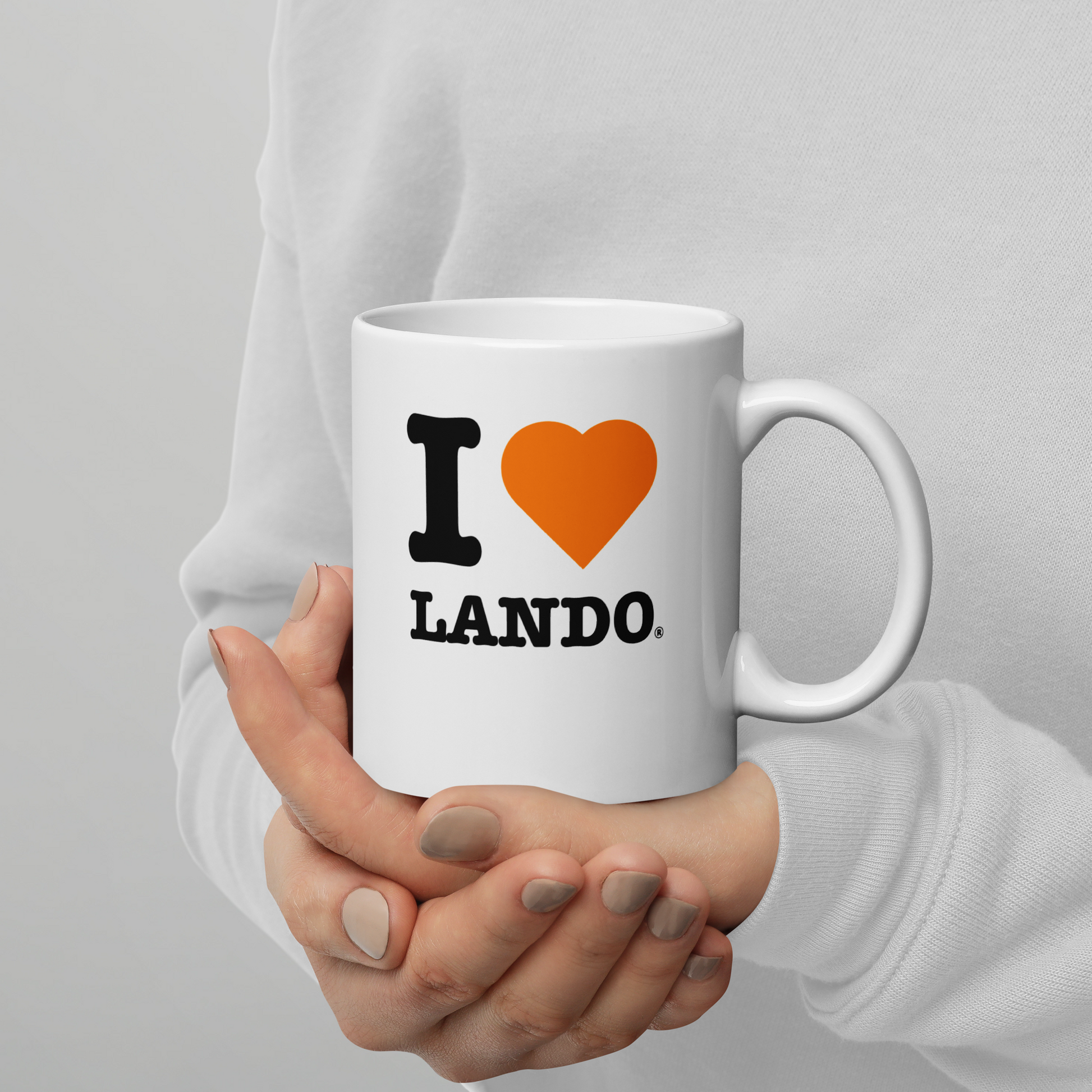 White mug with 'I ❤️ LANDO' text held by a person against a gray background. Ideal for Lando Norris fans.